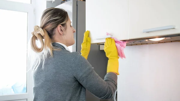 Bella giovane donna in guanti di lattice giallo lavaggio cucina — Foto Stock