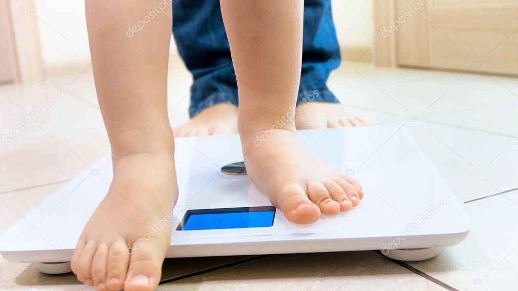 Closeup photo of baby feet next to mothers standing on digital scales