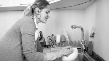 Siyah beyaz portre genç ev hanımı bulaşık gülümseyen ve kulaklık ile müzik dinleme