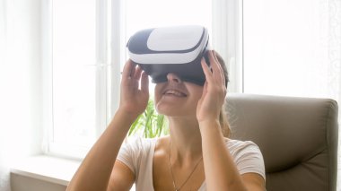 Closeup büyük pencere ofiste oturan Vr kask içinde gülümseyen genç kadın portresi