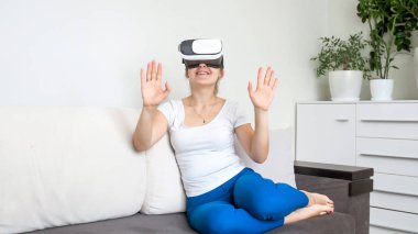 Kanepede oturan ve Vr kulaklık kullanarak güzel genç kadın