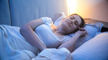 Geceleri yatakta uyuyan genç esmer kadın portresi