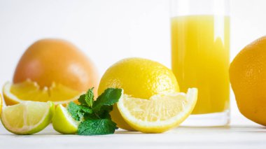 Portakal, limon ve greyfurt bardak portakal suyu Beyaz ahşap masa yanında portre resim