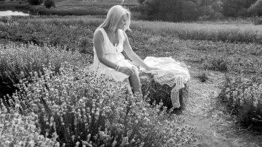 Saman yığınında alan üzerinde oturan genç kadın blak ve beyaz görüntü