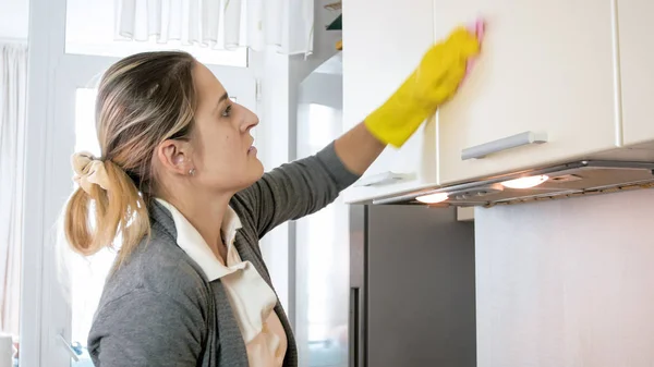 Porträt der schönen jungen Hausfrau, die Schränke mit Tuch wäscht — Stockfoto