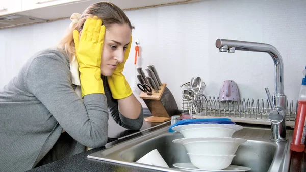 Портрет засмученої молодої домогосподарки, дивлячись на стос посуду — стокове фото