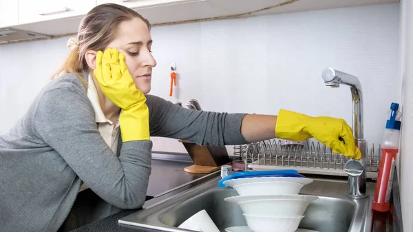 Портрет втомленої молодої домогосподарки відкриває водяний кран на кухні — стокове фото