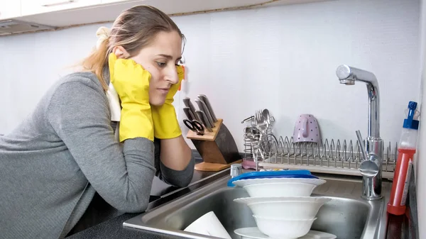 Verärgerte müde Frau blickt auf großen Haufen schmutziger Küchen in der Spüle — Stockfoto