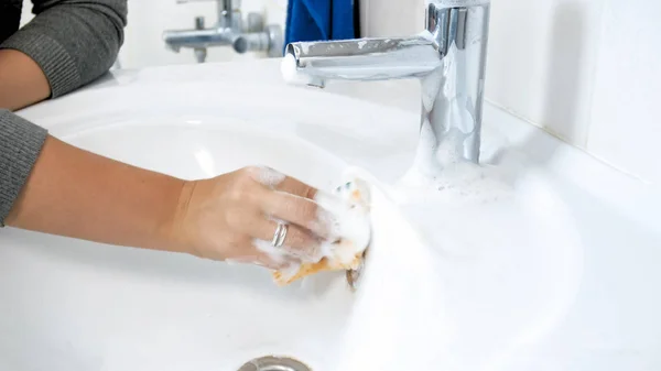 在肮脏的浴室水槽上使用清洁洗涤剂的年轻妇女特写照片 — 图库照片