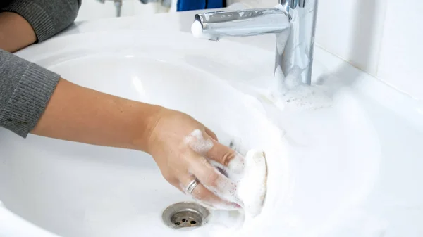 Closuep foto de mulher aplicando detergente suds na pia do banheiro sujeira — Fotografia de Stock