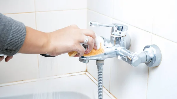 Foto de primer plano del grifo de agua de lavado de manos femenino en el baño con esponja —  Fotos de Stock