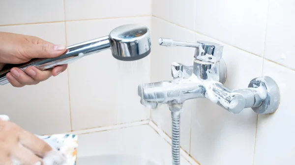 Imagem de close-up de uma jovem mulher limpando torneira de água no banheiro — Fotografia de Stock