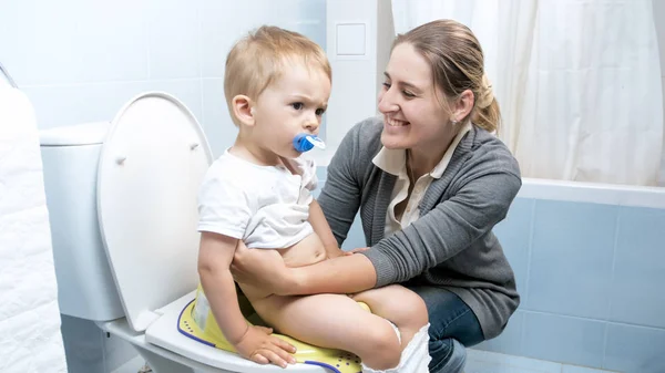 Счастливая веселая женщина учит своего малыша пользоваться туалетом — стоковое фото