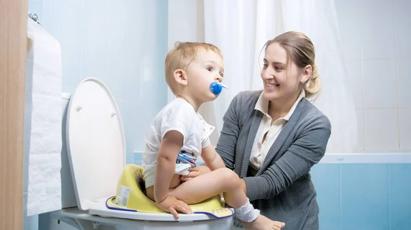 Fiatal anya mutatja a kisgyermek, hogyan kell használni a WC-vel — Stock Fotó