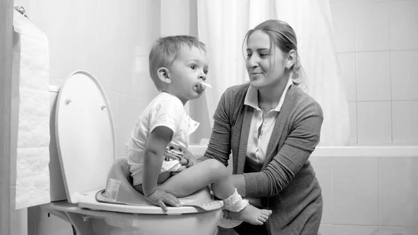 Imagen en blanco y negro de la joven madre enseñando a su hijo pequeño a usar el inodoro — Foto de Stock