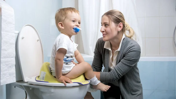 Nuori äiti selittää hänen lapsi poika miten käyttää wc — kuvapankkivalokuva