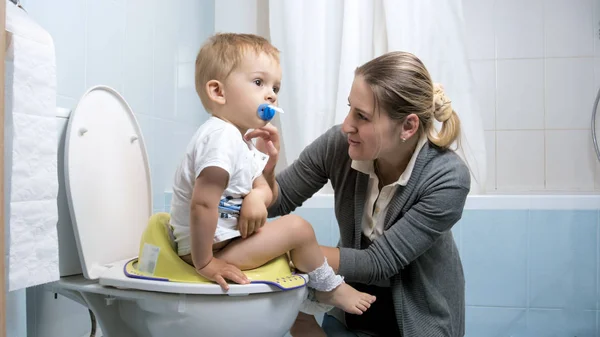 Giovane madre insegnando il suo bambino di 2 anni ragazzo utilizzando toilette — Foto Stock