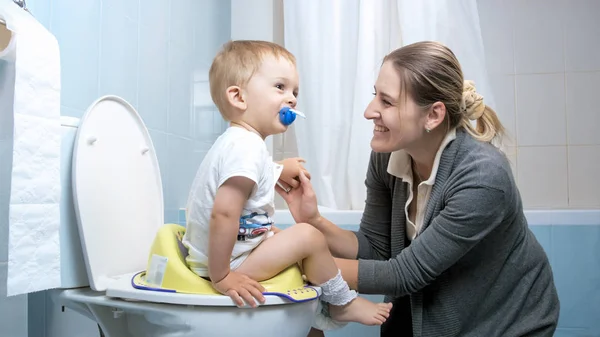 Giovane madre sorridente dopo il suo bambino ragazzo usato toilette — Foto Stock