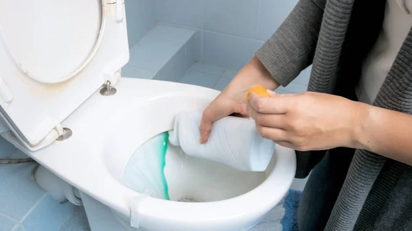 Imagen de primer plano de una mujer joven vertiendo detergente antibacteriano en el inodoro —  Fotos de Stock