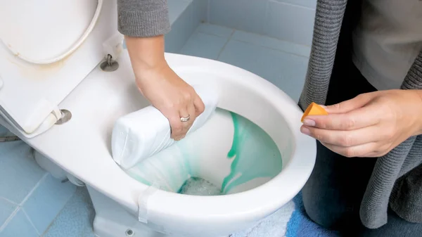 Närbild bild av ung kvinna hälla antibakteriella rengöringsvätska i toalett — Stockfoto