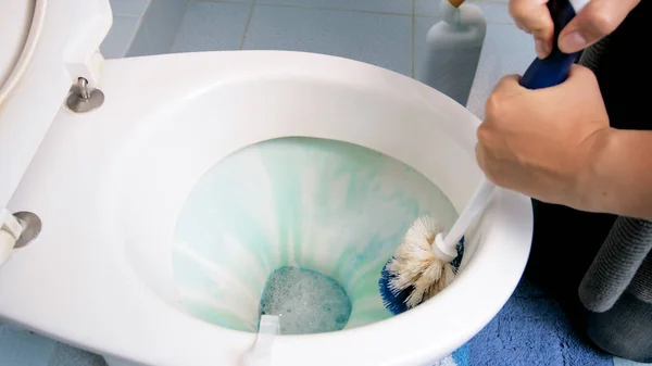 Крупный план уборки туалета молодой женщиной после нанесения моющего средства — стоковое фото