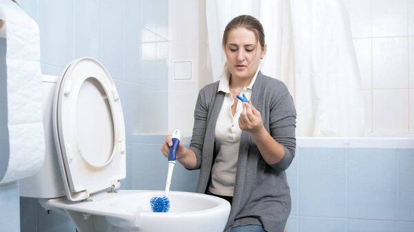 Портрет молодой женщины, закрывающей нос перед мытьем туалета
