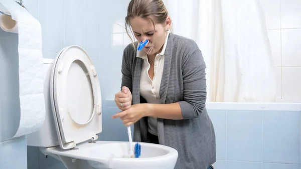 Молодая женщина чистит туалет и пытается избавиться от дурного запаха — стоковое фото