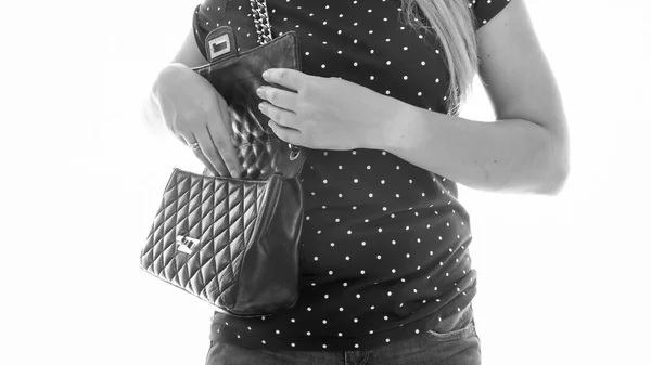 Black and white image of young woman looking inside of her handbag — Stock Photo, Image
