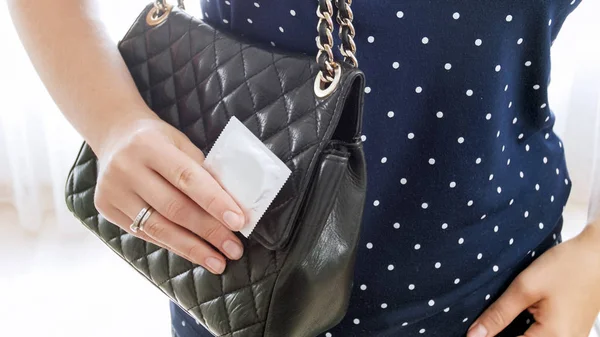 Photo isolée rapprochée de jeune femme avec sac à main montrant le préservatif — Photo
