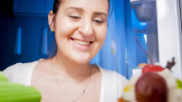 Retrato de una hermosa mujer joven mirando dentro del refrigerador por la noche —  Fotos de Stock