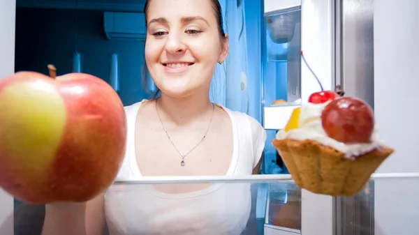 Portrait of beautiful smiling woman looking for food at night — Stock Photo, Image