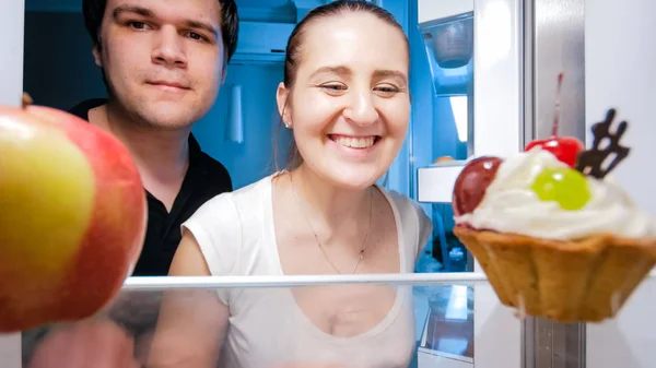 Closeup portrait of smiling young family looking inside of refrigerator — Stock Photo, Image