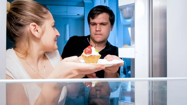 Closeup portrait of young hungry couple fighting for last piece of cake at night — Stock Photo, Image