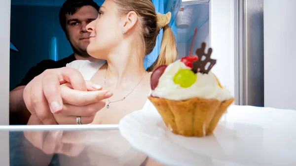 Young man stopping his wife from eating cake at night — Stock Photo, Image