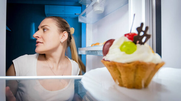 Closeup portrait of young woman sneaking in refrigerator for something to eat