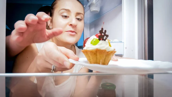 Young man traying to take cake his wife took from refrigerator at night — Stock Photo, Image