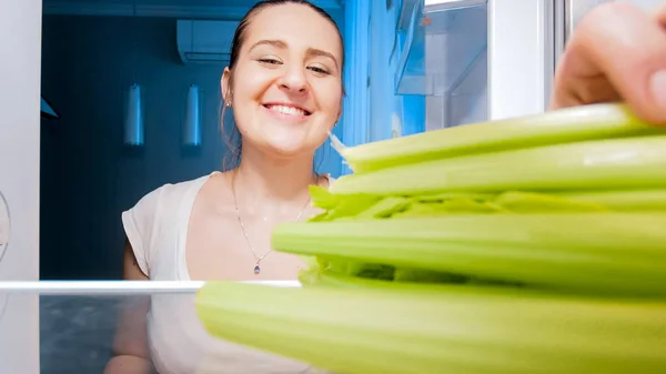 Primer plano retrato de feliz sonriente mujer takig apio de refrigerador estante —  Fotos de Stock