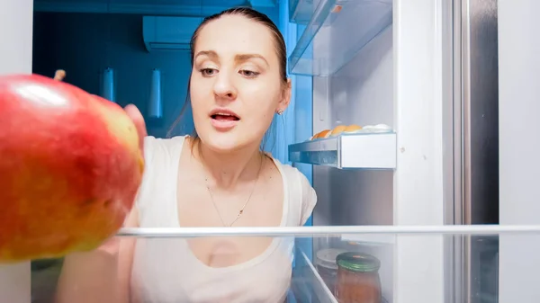 Imagen de cerca de una joven hambrienta buscando algo para comer en el refrigerador por la noche —  Fotos de Stock