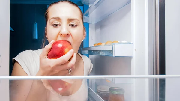 Portrait of young woman sneaking in refrigerator at night — Stock Photo, Image