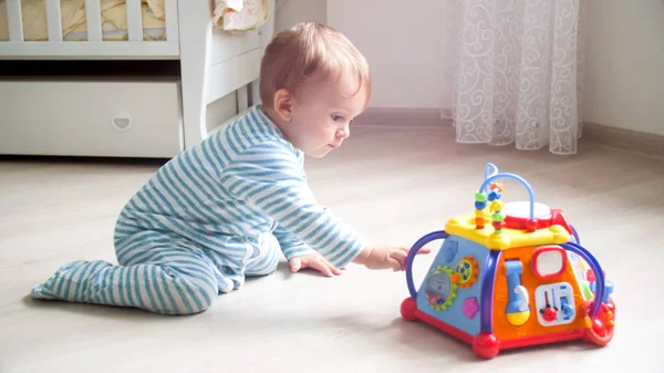 Очаровательный мальчик играет с электронной игрушкой на полу в гостиной — стоковое фото