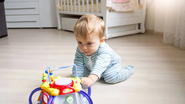 Söt 1 år gamla barn pojke sitta på golvet vid sovrum och leker med leksaker — Stockfoto