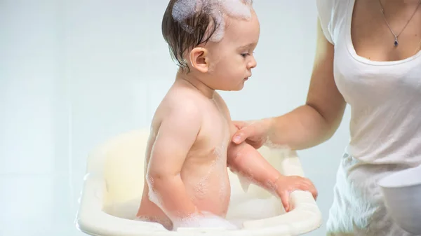 Retrato de niño lindo con suds en el lavado de cabeza en bañera de plástico — Foto de Stock