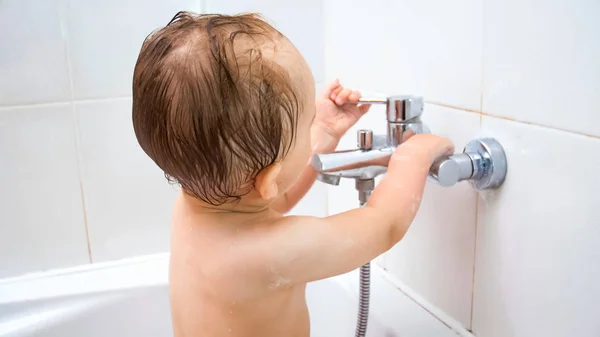 Imagen de primer plano de niño de 1 año abre grifo de agua en el baño — Foto de Stock