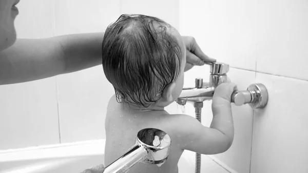 Banyoda ve su musluk ile oynarken yürümeye başlayan çocuk imajının siyah ve beyaz — Stok fotoğraf