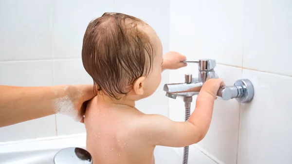 Imagen de primer plano de niño lindo bañándose y jugando con el grifo de agua — Foto de Stock
