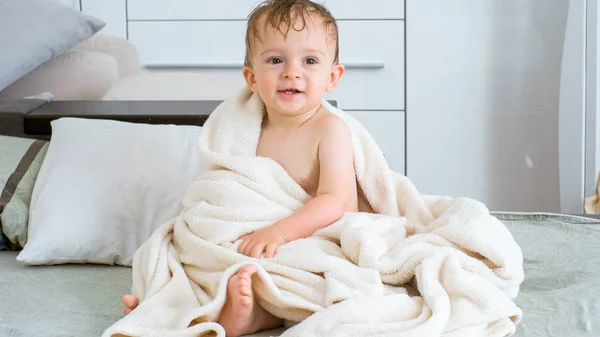 Retrato de 1 ano de idade criança menino coberto de toalha branca sentado na cama — Fotografia de Stock
