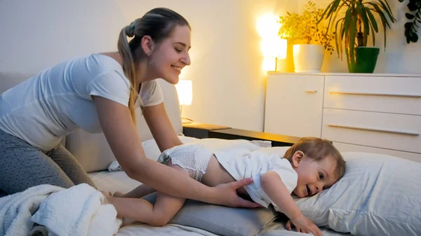 Boldog, fiatal nő, ő kisgyermek fia az ágyban éjjel — Stock Fotó