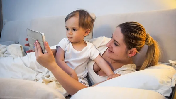 Retrato de menino bonito criança deitado com a mãe na cama e assistindo desenhos animados — Fotografia de Stock