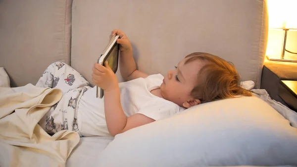 Portret van schattige kleuter jongen met digitale tablet in bed bij nacht — Stockfoto