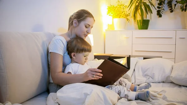 Retrato de una hermosa madre joven leyendo la historia a su hijo pequeño —  Fotos de Stock